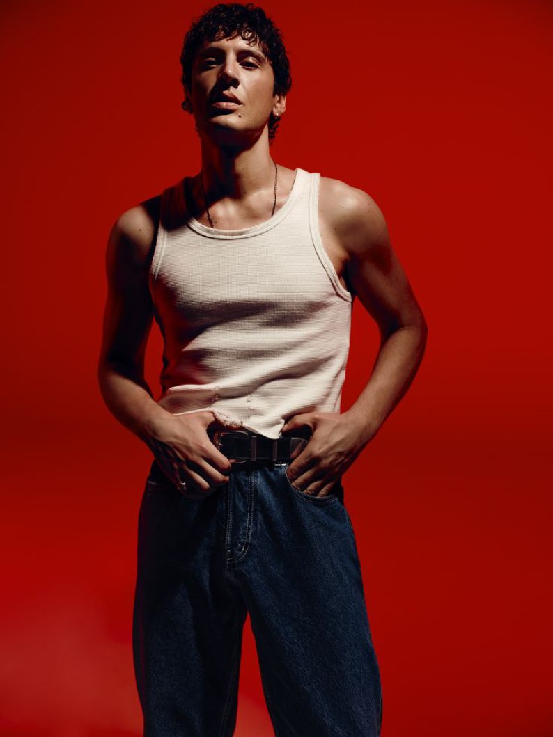 Model in a white tank and dark indigo DL935 jeans against a red studio backdrop